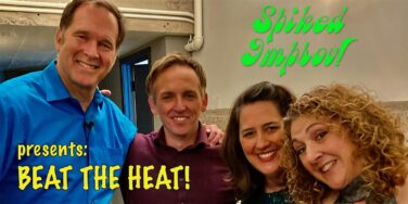 Group of smiling people posing for a photo with neon green 'Spiked Improv!' text and yellow 'Beat The Heat!' lettering on a wall behind them.