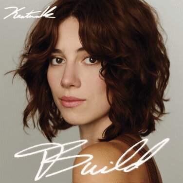 Close-up portrait of a woman with wavy brown hair, looking slightly to the left, with white cursive text overlaid on a gray background.