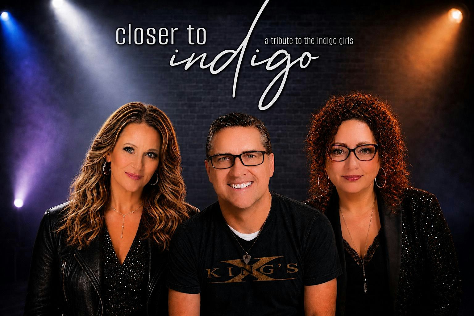 Promotional image for 'Closer to Indigo,' a tribute to the Indigo Girls, featuring three performers (two women flanking a smiling man) under stage lights.