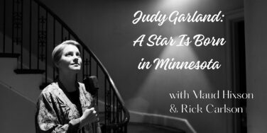 Black-and-white photo of Judy Garland speaking into a microphone near a staircase with a promotional banner reading 'Judy Garland: A Star Is Born in Minnesota' on the right.
